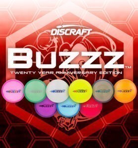 This graphic features a gradient background of hexagons fading from pink, to red, to dark red from top to bottom. At the centre is a larger overlaying hexagon, containing text: Discraft Buzzz Twenty Year Anniversary Edition. Below the text are two rows of all the different styles and colours that the disc comes in: pink, green, white, yellow, gray and brown, orange, purple, blue, and lastly red